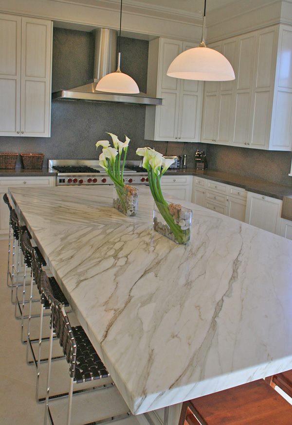Natural Elegant kitchen with a large white marble island featuring gray veining, pendant lights, and white cabinetry